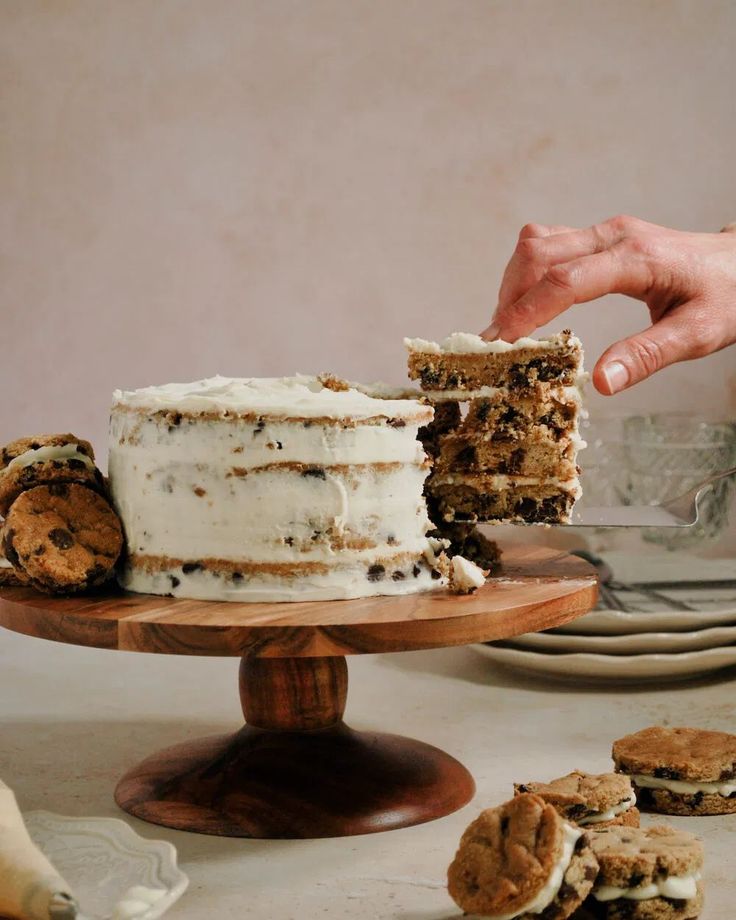 someone is cutting into a cake with cookies on the side