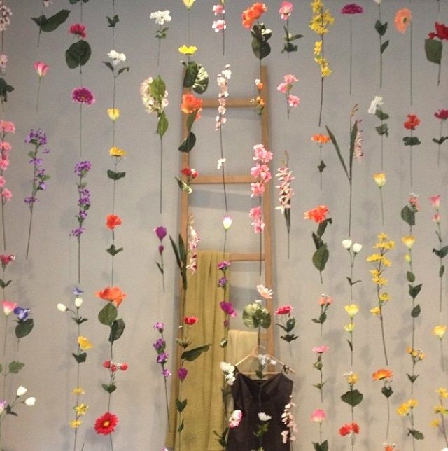 a room filled with lots of fake flowers hanging from the ceiling and on top of a ladder