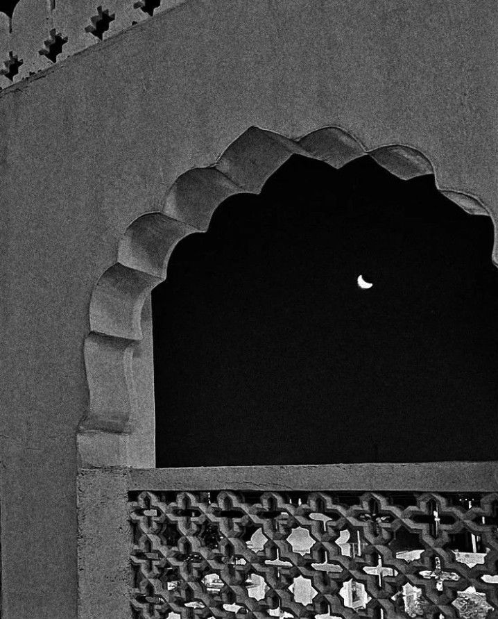 a black and white photo of a window with a moon in the background