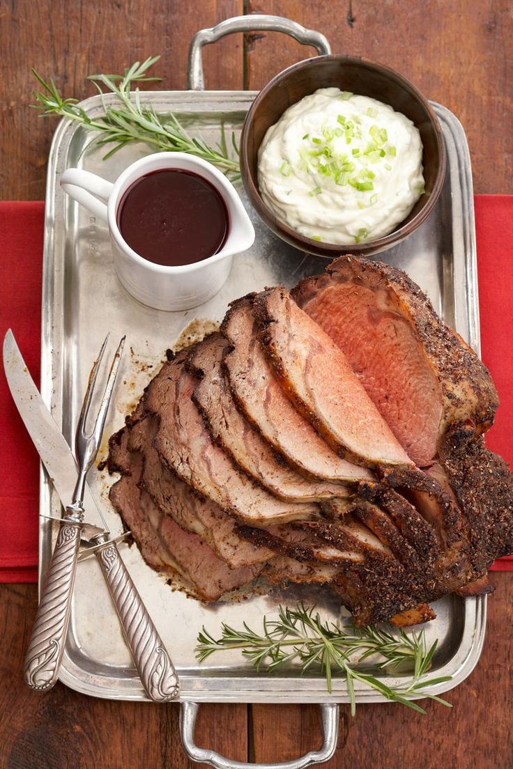 a tray with meat, mashed potatoes and sauces on it next to utensils