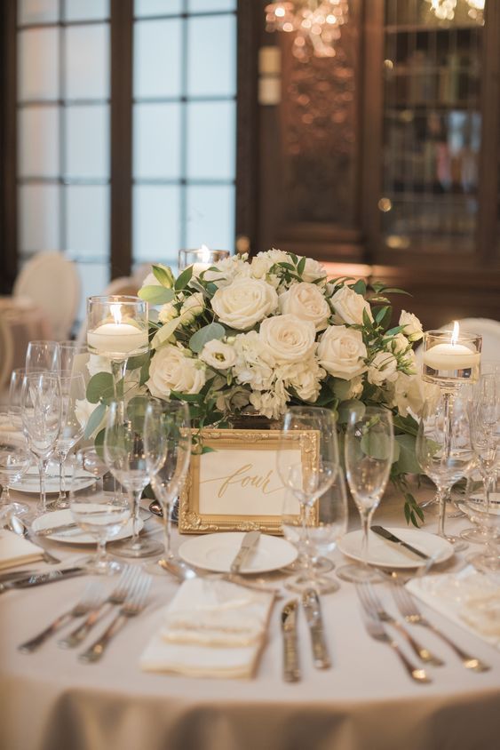 a table set with white flowers and silverware for a formal dinner or wedding reception