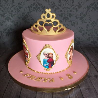 a pink and gold cake with an image of a princess on it's side