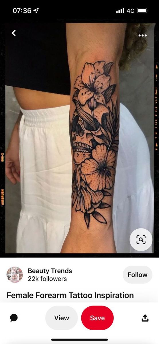 a woman's arm with a skull and flowers on it