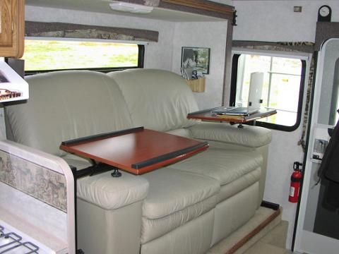 a couch and table in the back of a camper with an open door to another room