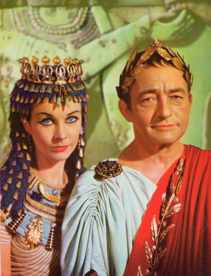 a man and woman dressed in ancient greek costumes pose for the camera, both wearing tiaras