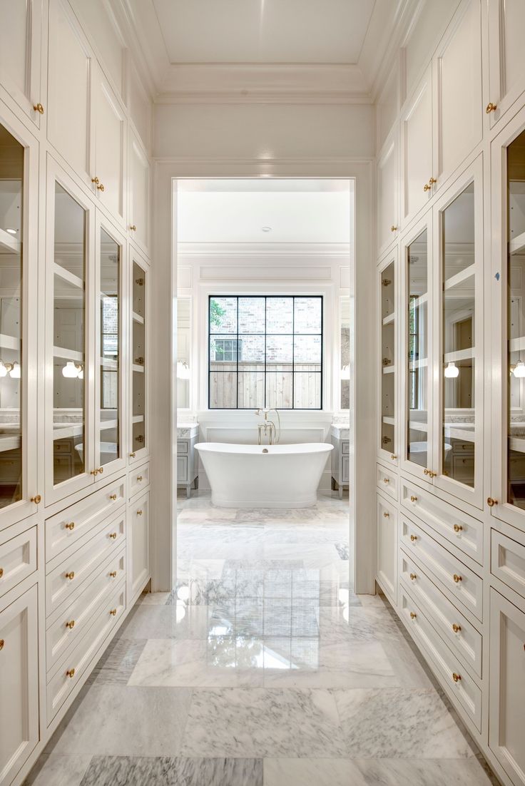 a white bathroom with marble floors and cabinets