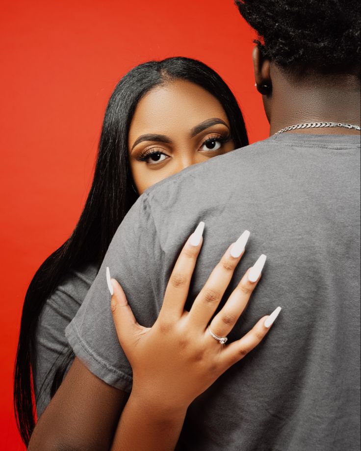 a woman hugging a man in front of a red background