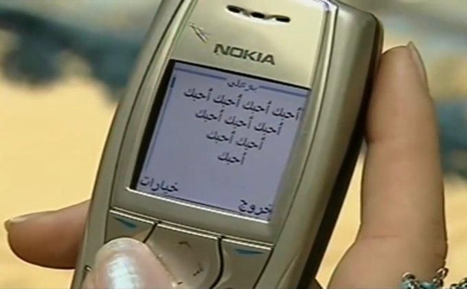 a person holding an old nokia cell phone in their hand with arabic writing on the screen