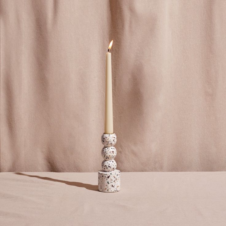 a white candle sitting on top of a stack of rocks