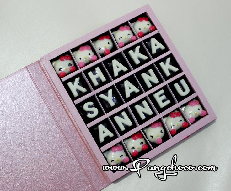 a pink box filled with hello kitty magnets on top of a white tablecloth