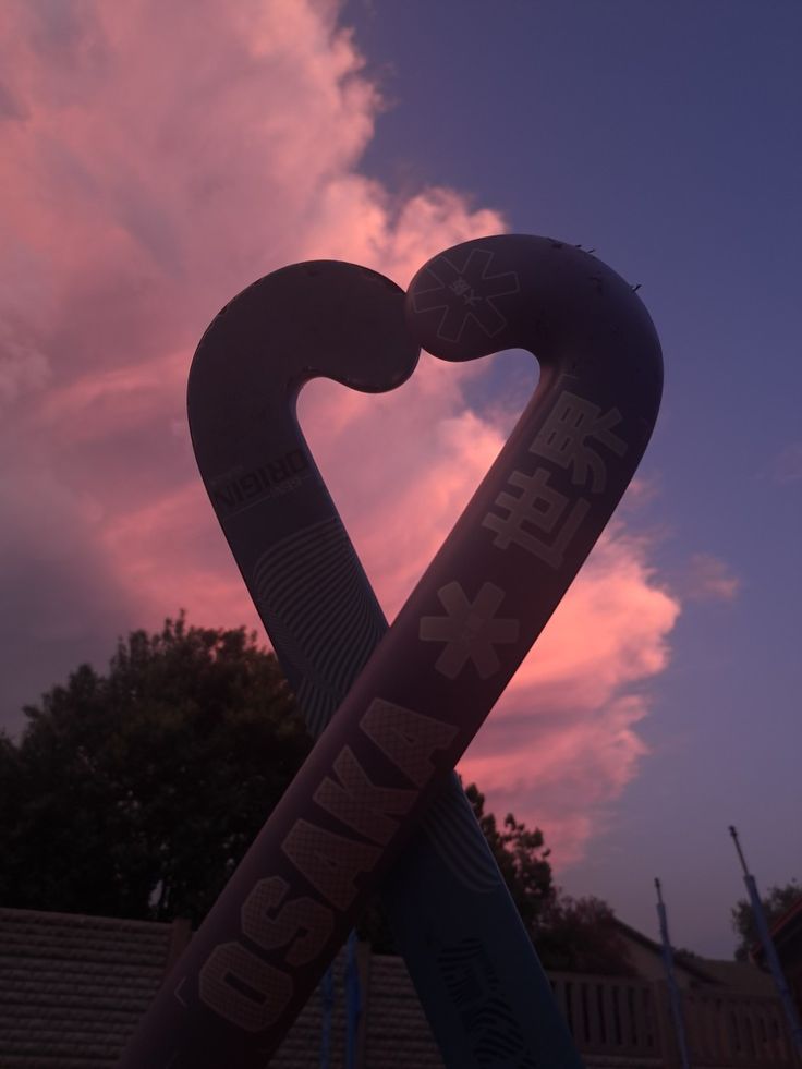 an inflatable heart shaped sign with the sky and clouds behind it at sunset