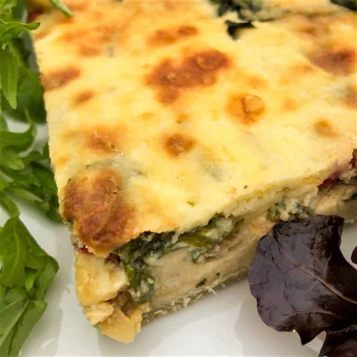 a slice of quiche on a plate with greens