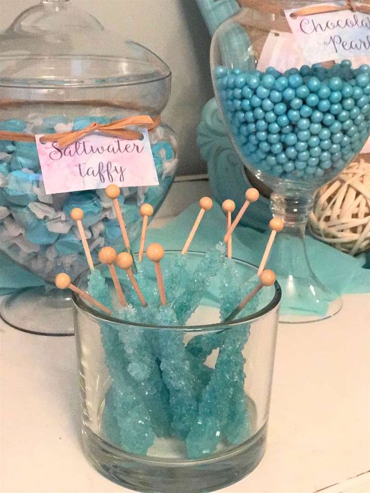 there are many candies in the glass vases on the table with name tags