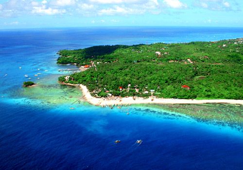 an island in the middle of the ocean with boats floating on it's sides