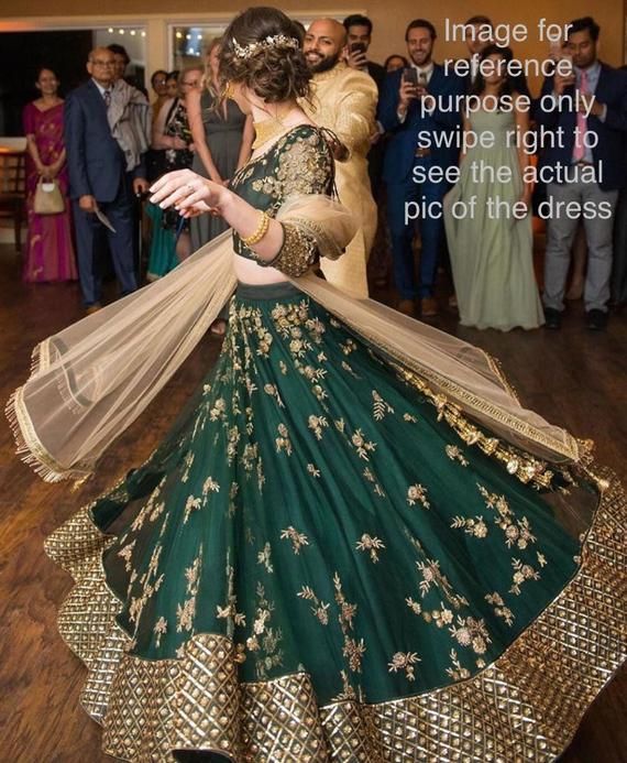 a woman in a green and gold lehenga dancing on the dance floor at a wedding