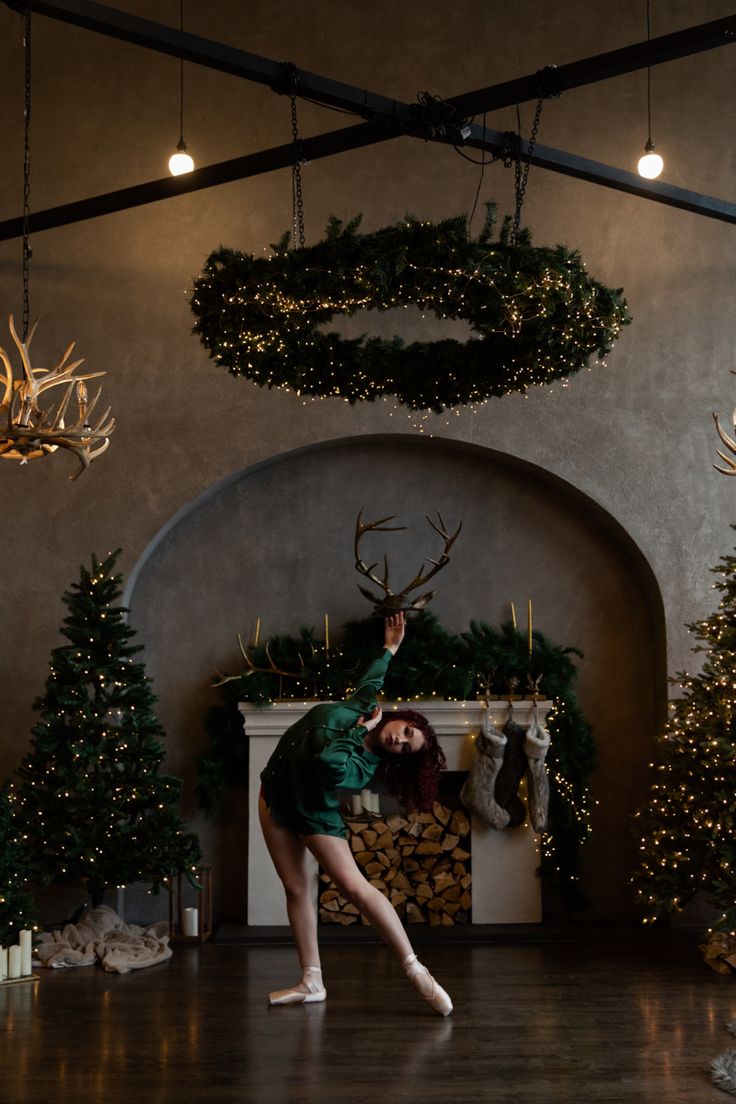 a woman is dancing in front of christmas trees and wreaths on the fireplace mantel