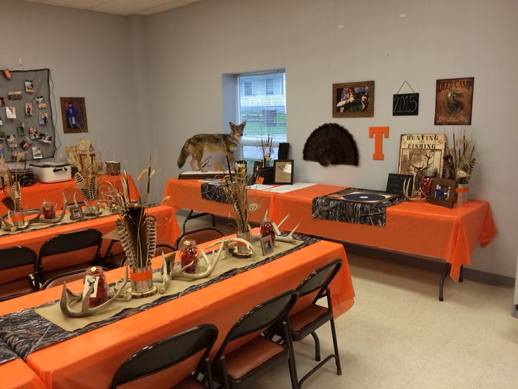 an orange table cloth is on top of the tables in this room with pictures and deer heads