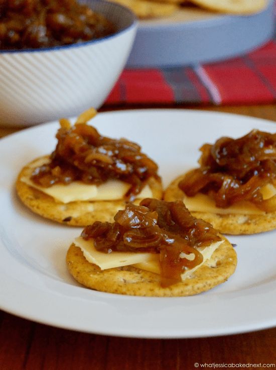 three crackers topped with jelly and cheese on a plate next to a bowl of chili