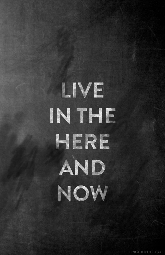 the words live in the here and now written on a blackboard