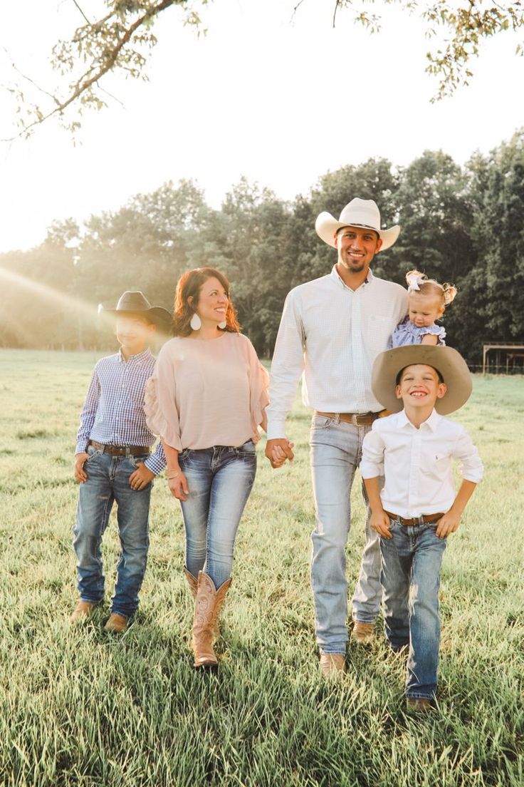 a man, woman and two children are walking in the grass