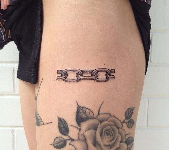 a woman's thigh with a rose and chain tattoo on her lower half leg