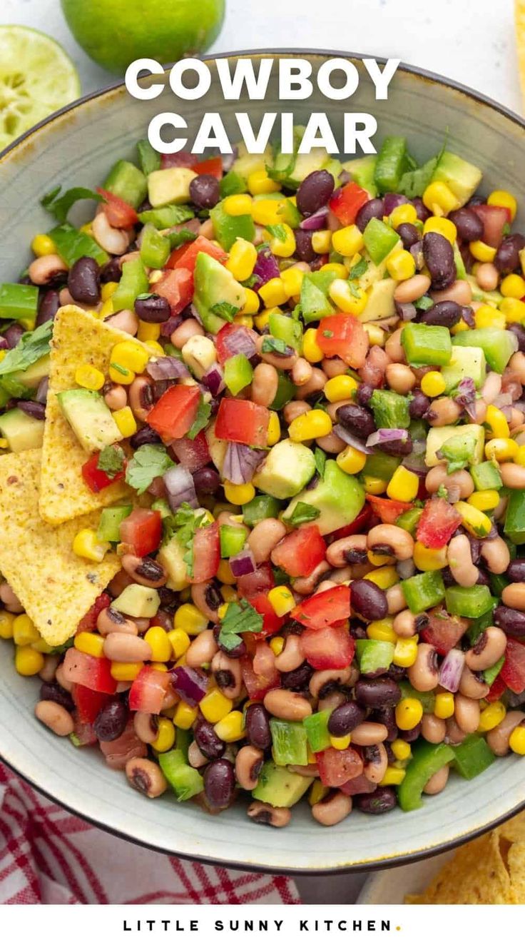 a bowl filled with black - eyed beans, corn and avocado next to tortilla chips