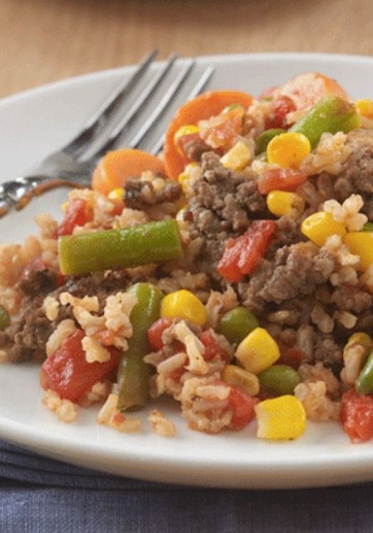 a white plate topped with rice covered in meat and veggies next to a fork