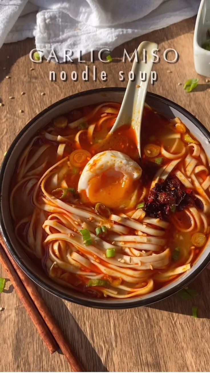 a bowl of noodle soup with an egg on top and chopsticks next to it