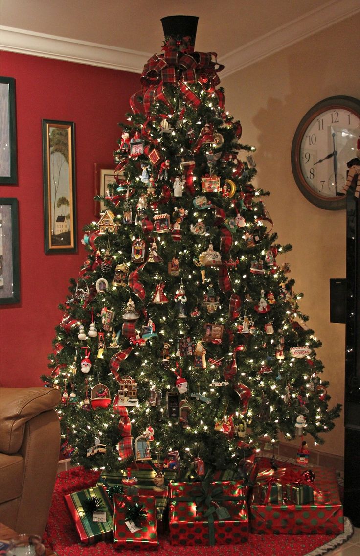 a christmas tree with presents under it in a living room next to a wall clock