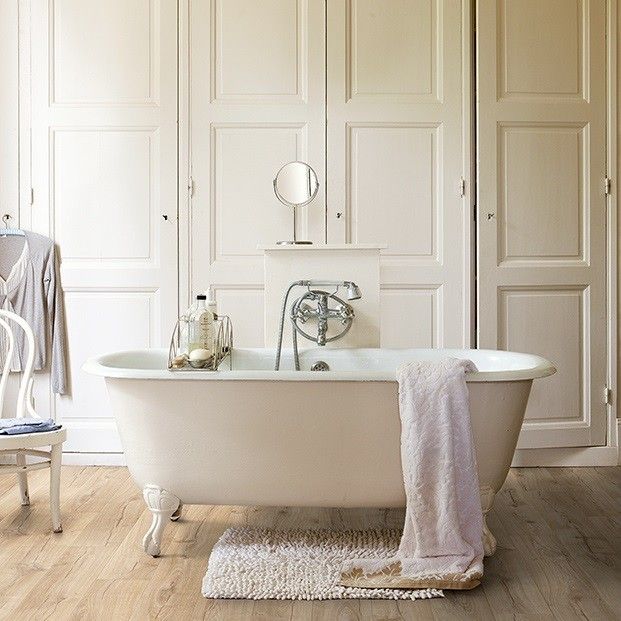 a white bath tub sitting in a bathroom next to a chair