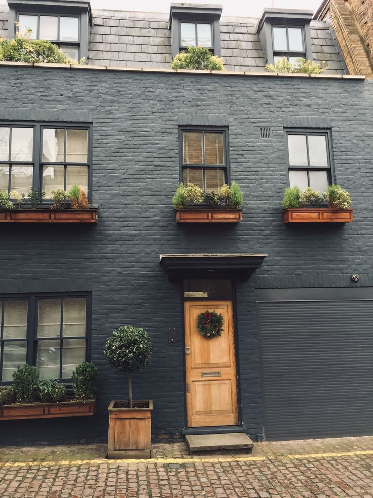 a black building with windows and potted plants on the front door, along with two wooden planters