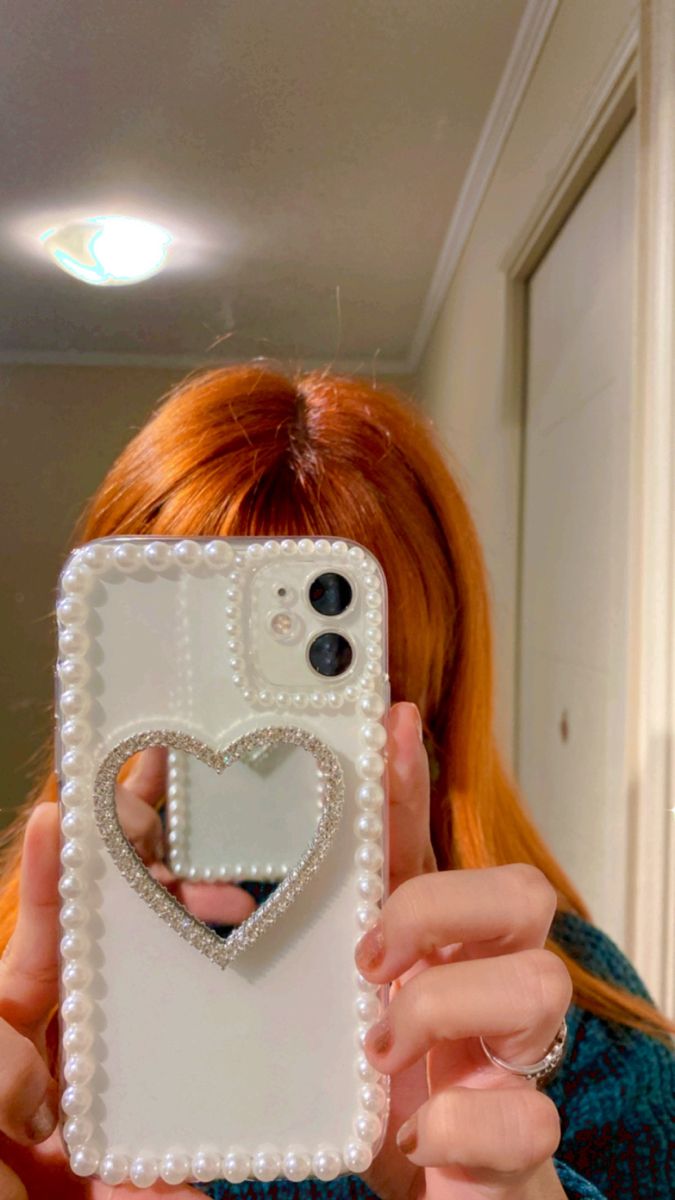 a woman taking a selfie in front of her cell phone with a heart on it