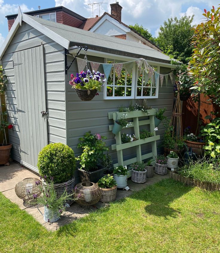 a garden shed with potted plants and hanging baskets