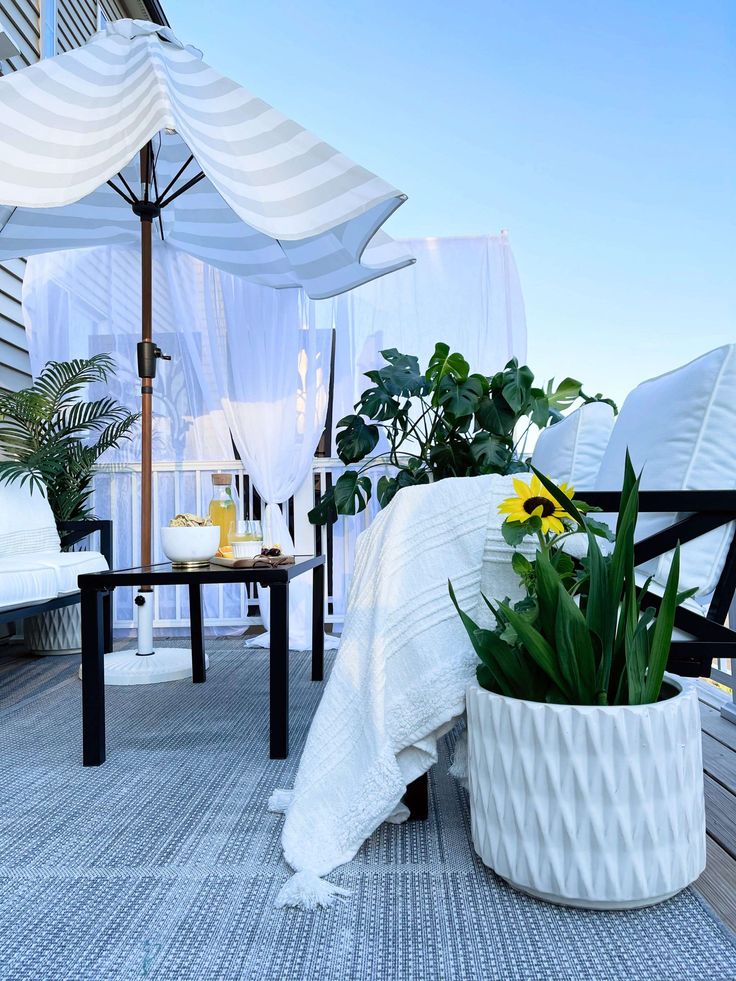 there is a bed with white sheets and flowers in the planter on the balcony