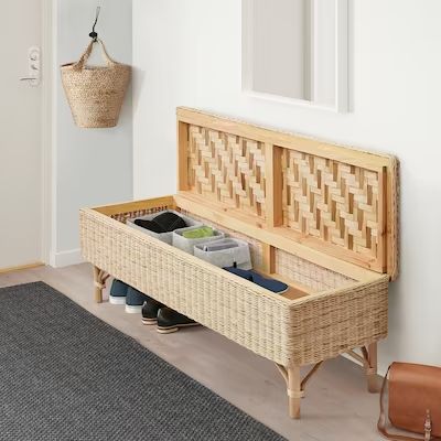 a wooden bench with baskets and shoes on it next to a rug in a room