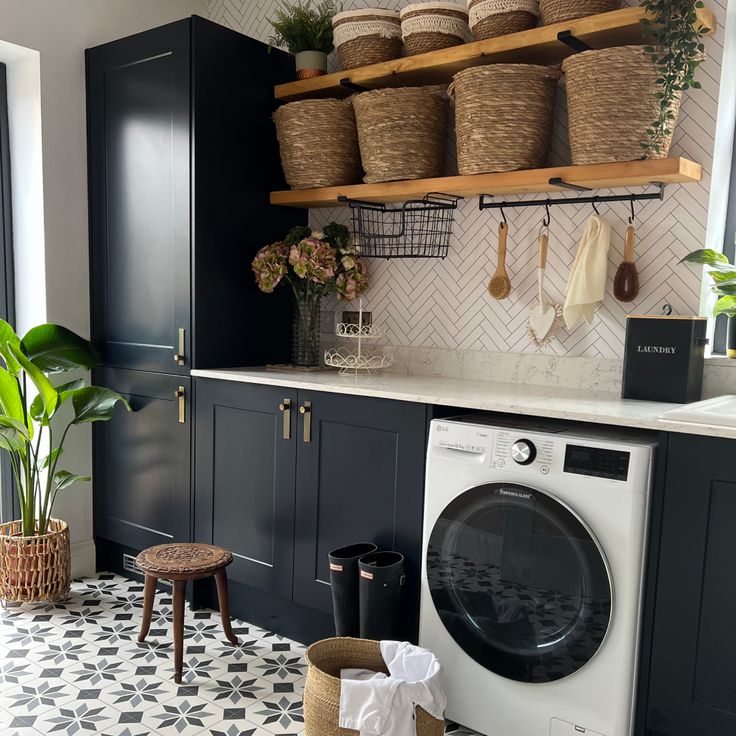 a washer and dryer in a room with black cabinets, white tile flooring and hanging baskets on the wall