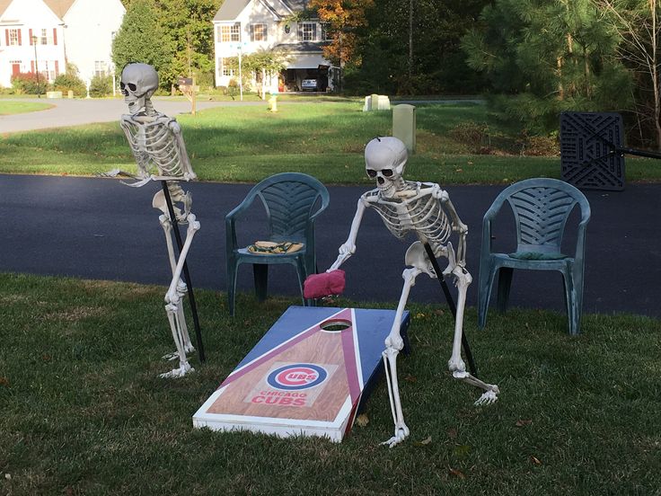 two skeletons playing cornhole game in the yard