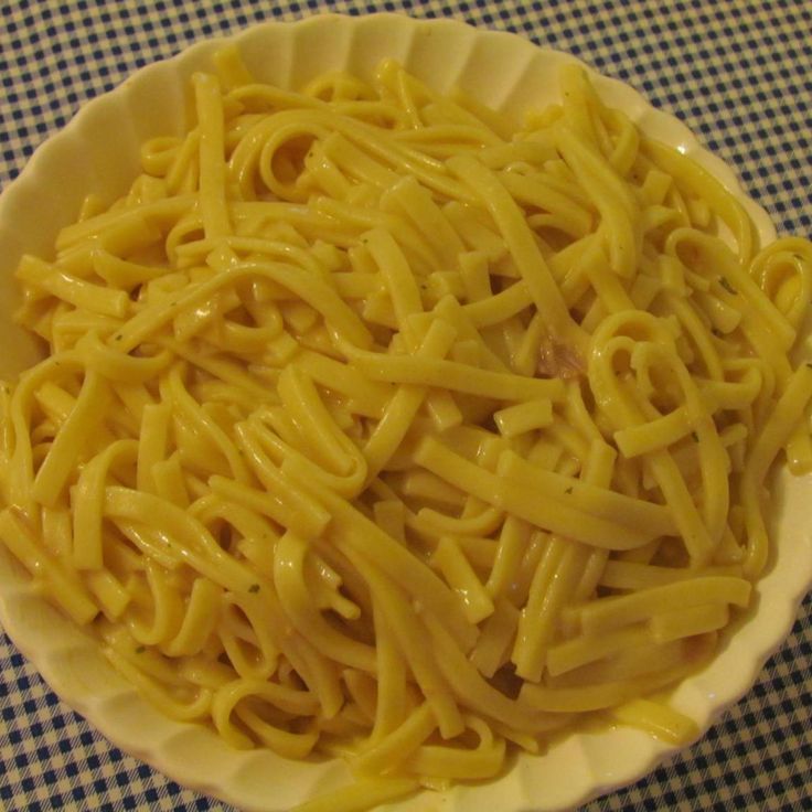 a white bowl filled with noodles sitting on top of a blue checkered table cloth