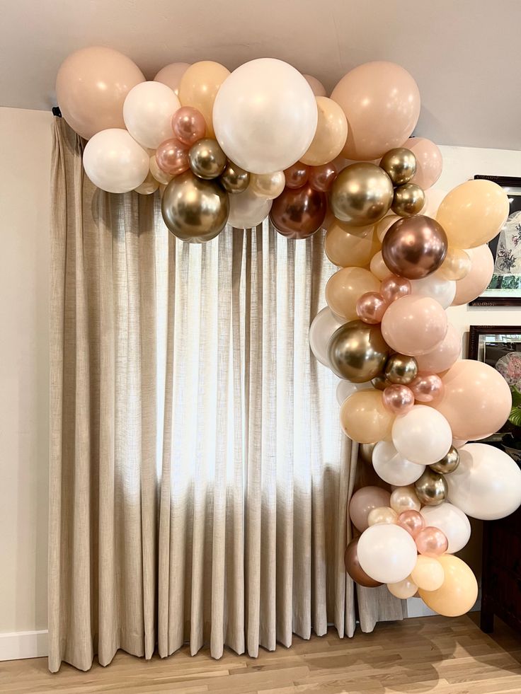 a bunch of balloons that are in front of a curtain with curtains behind them and some pictures on the wall