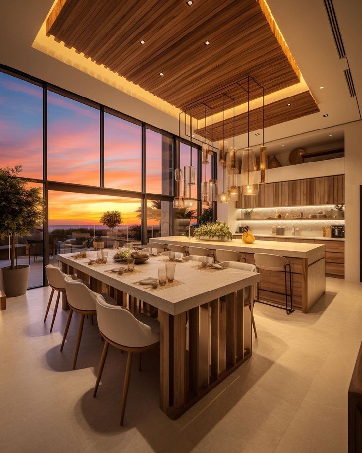 a large kitchen with an island and dining table in the middle of it at sunset