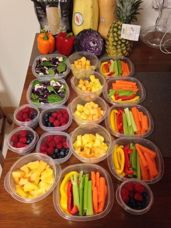 there are many different fruits and vegetables in plastic containers on the table with pineapples