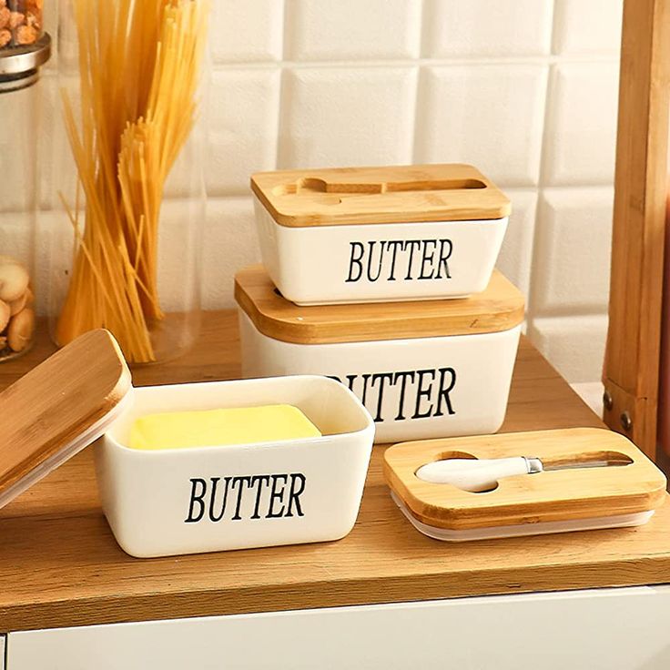 three white bowls with butter on them sitting on a counter next to some pasta and other ingredients