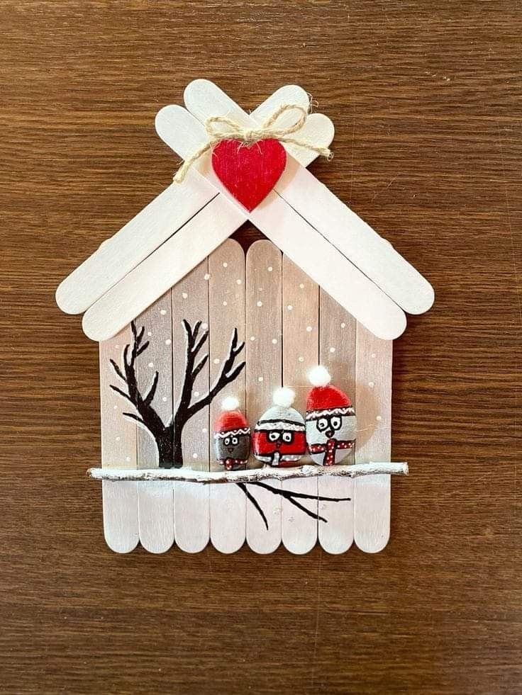 a wooden house with two red hearts on it's roof and trees in the window