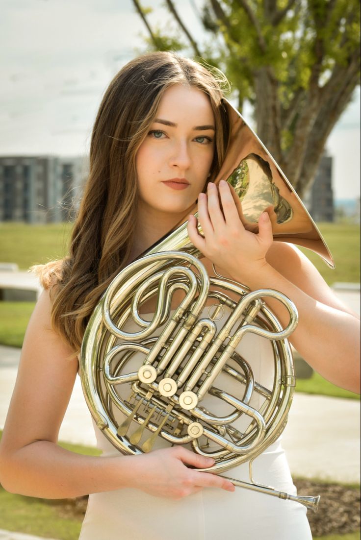 a woman holding a french horn in her hands