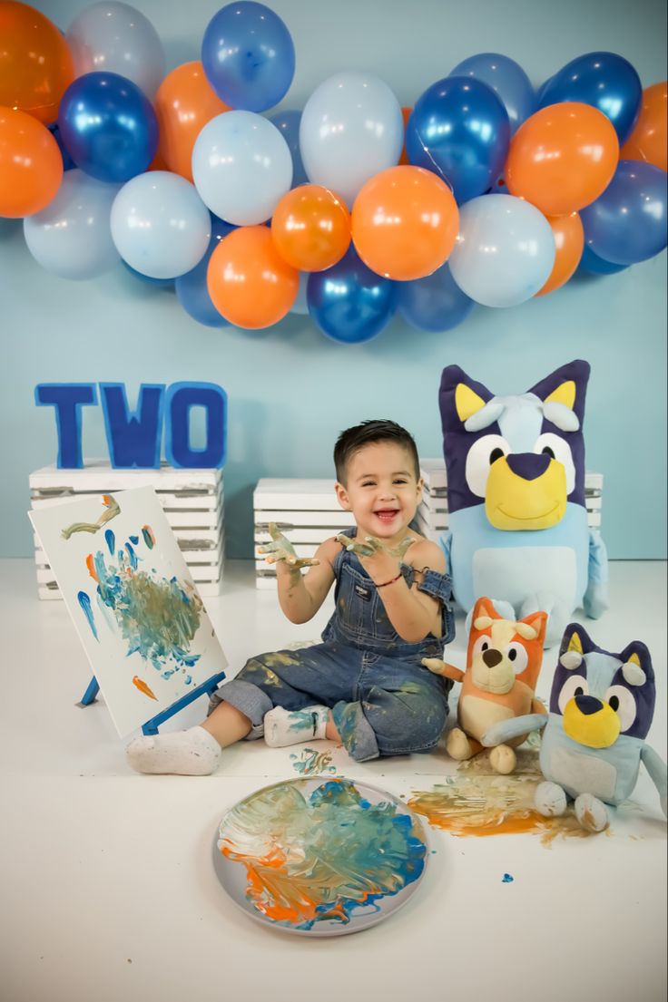 a little boy sitting in front of some balloons