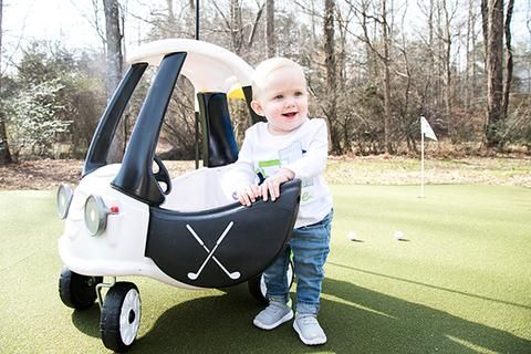 a little boy standing next to a golf cart