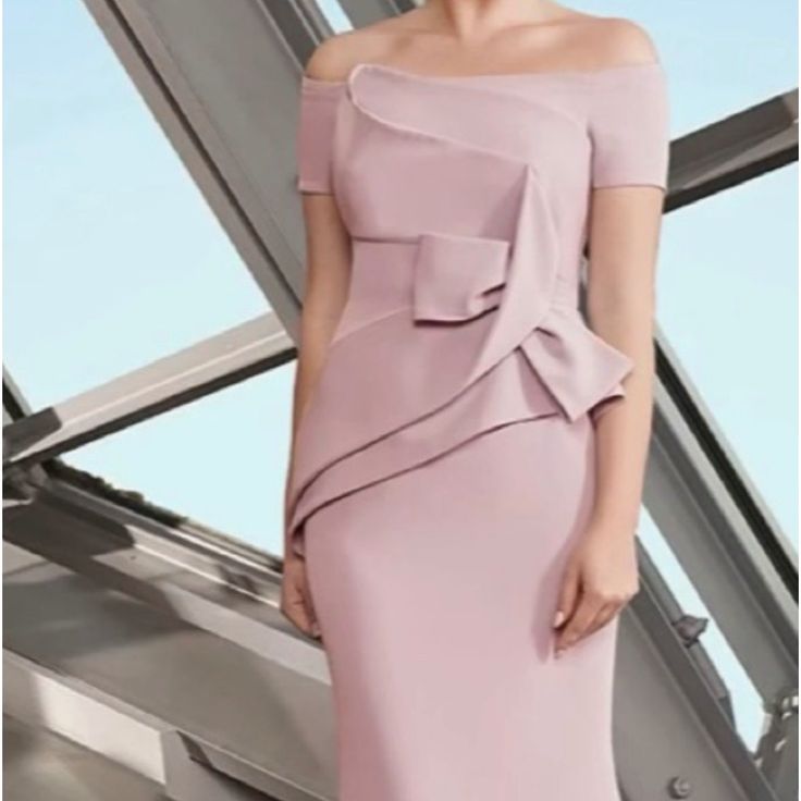 a woman in a pink dress standing next to a window with her hands on her hips