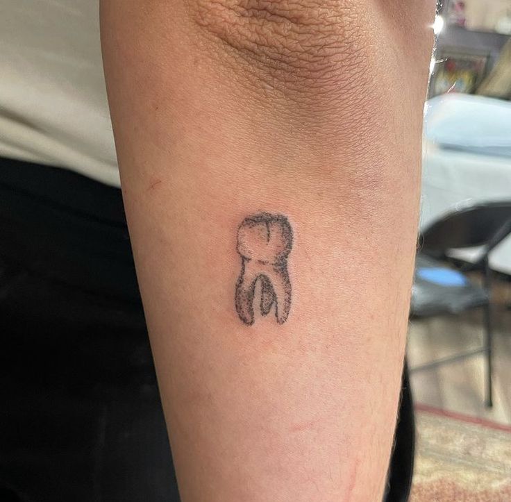 a small tattoo on the arm of a person with a toothbrush in it's mouth