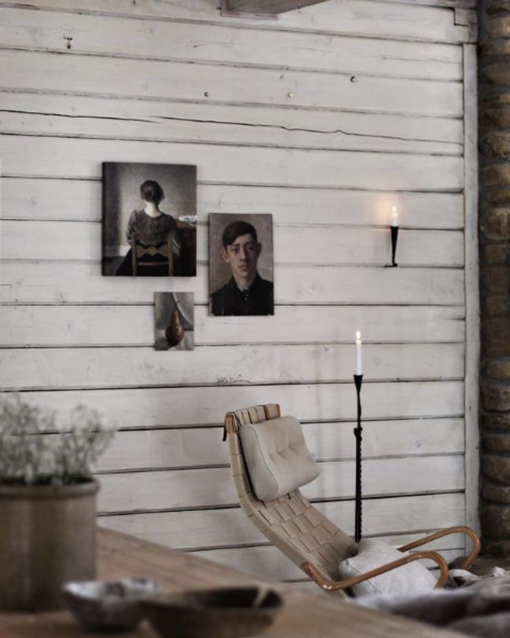 a room with two pictures on the wall and a chair in front of it next to a candle