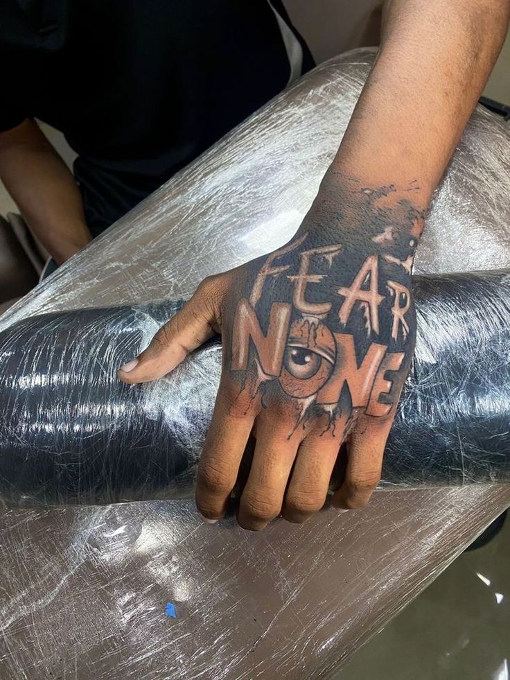 a hand with the words fear and no one on it is holding onto a piece of tin foil